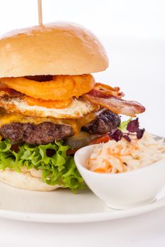 Delicious egg and bacon cheeseburger with a nutritional filling of salad ingredients, a ground beef patty, cheese, fried egg and crispy bacon on a white crusty roll