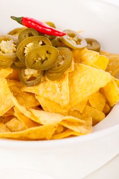 Bowl of crisp golden corn nachos with cheese sauce or dip and olives served as a starter or appetizer to a meal