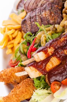 Wholesome platter of mixed meats including grilled steak, crispy crumbed chicken and beef on a bed of fresh leafy green mixed salad served with French fries and chutney or BBQ sauce in a dish