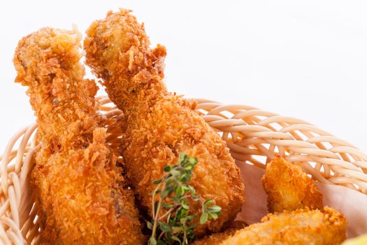 Crisp crunchy golden chicken legs and wings deep fried in bread crumbs and served with a bowl of dip in a wicker basket for a delicious appetizer