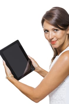 Attractive young business woman standing chatting on a mobile while simultaneously reading a tablet computer with a smile, isolated on white