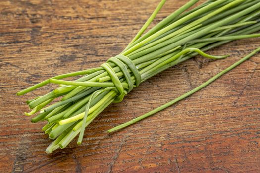 bunch of fresh green chives against rustic grunge wood