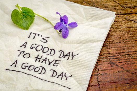 it is a good day  to have a good day - handweiting on a cocktail napkin with a viola flower