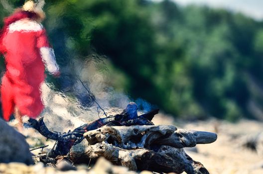 Woman in red dress near the campfire on the coast