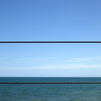 Blue ocean viewed from a metal wired fence