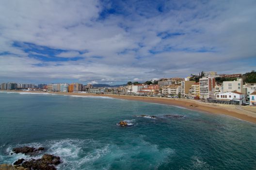 Coastline and View on Apartment Buildings and House Facades on Cloudy Blue Sky background, Blanes, Spain