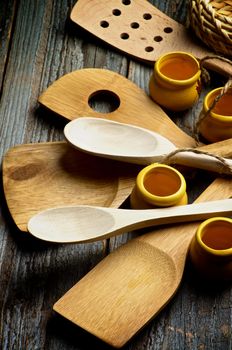 Arrangement of Kitchen Utensils with Wooden Spoons, Spatula and Small Pots closeup on Rustic Wooden background