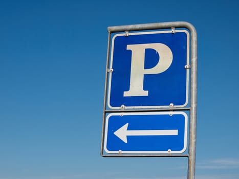 Parking symbol sign with direction arrow with clear blue sky background