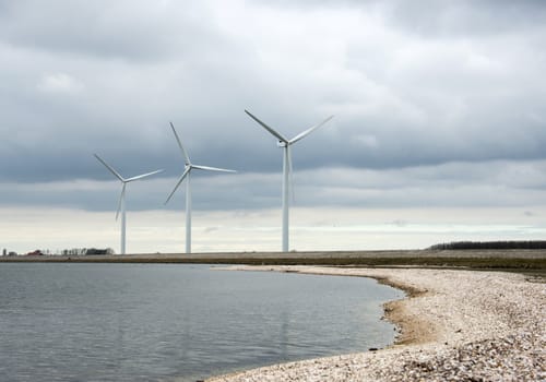 three windmills in Holland near a water lake