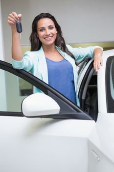 Smiling customer showing her new key at new car showroom