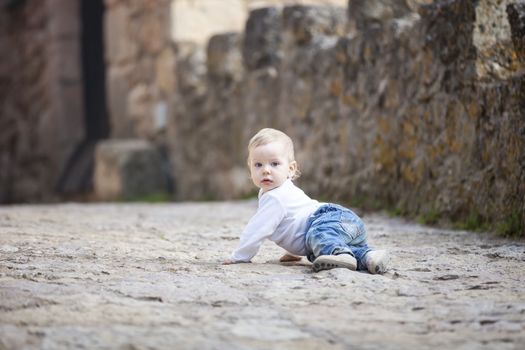 Little boy crawling on stone paved sidewalk