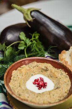 Traditional arabian eggplant dip baba ganoush with herbs and smoked paprika on a wooden background