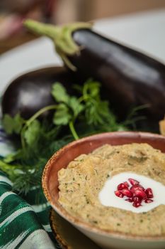 Traditional arabian eggplant dip baba ganoush with herbs and smoked paprika on a wooden background