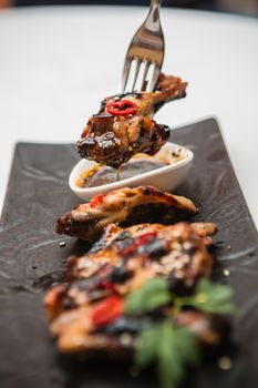 Hot organic chicken wings with red pepper on black dish