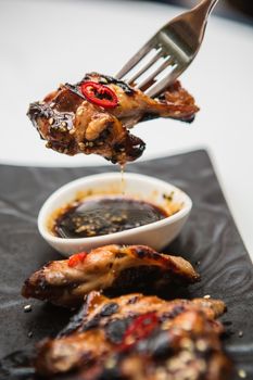 Hot organic chicken wings with red pepper on black dish