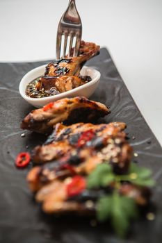 Hot organic chicken wings with red pepper on black dish