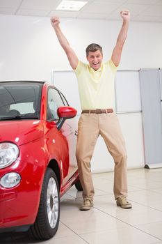 Happy customer cheering at camera at new car showroom