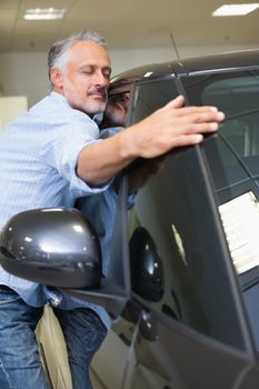 Man hugging on a car at new car showroom