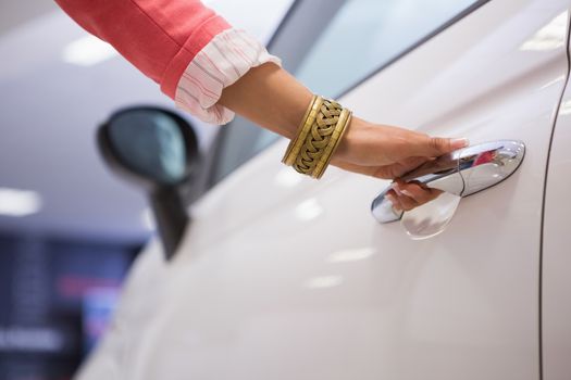 Woman holding a car door handles at new car showroom