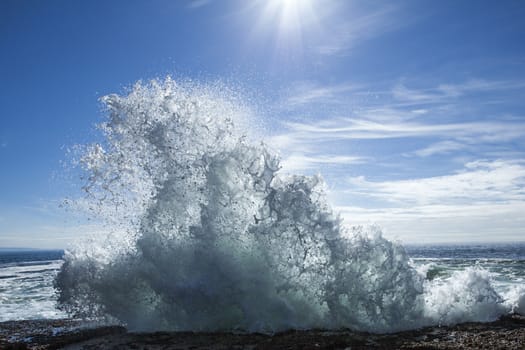 Wave crashing over rocks in the sunshine