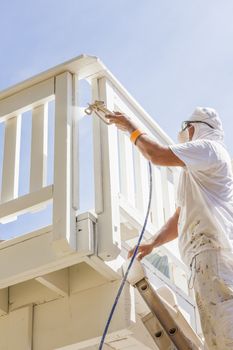 House Painter Wearing Facial Protection Spray Painting A Deck of A Home.