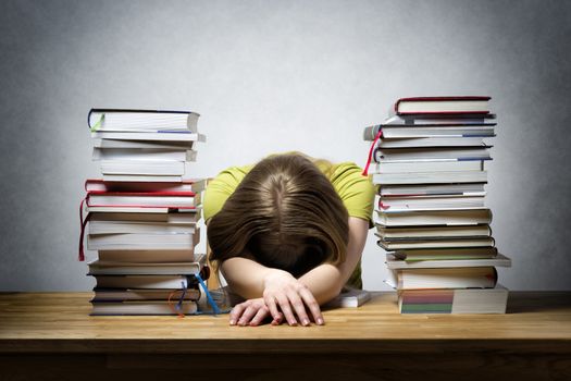 Very overworked female student at a table with lots of books