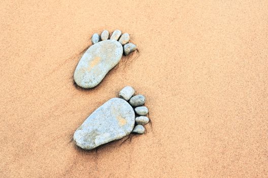 Stone footprints in the sandy beach
