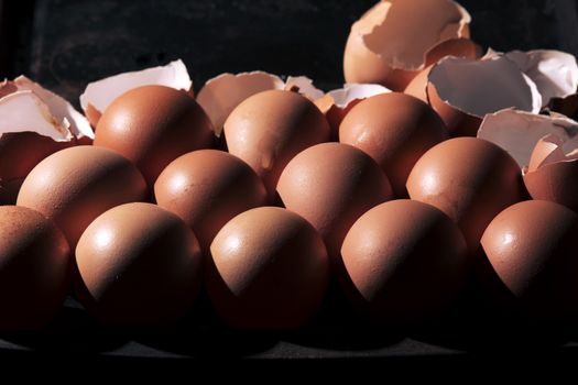 Low light with high contrast lighting of a bunch of eggs whole and crushed shells.