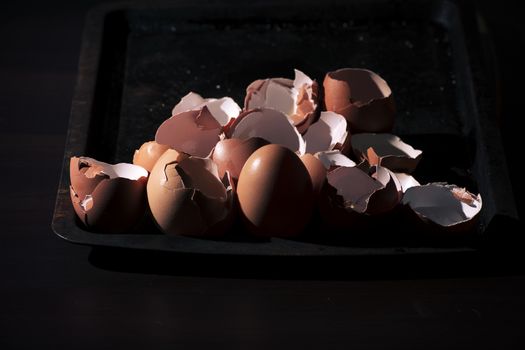 Low light with high contrast lighting of a bunch of eggs whole and crushed shells.