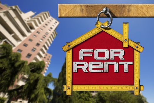 Yellow wooden meter ruler in the shape of house with text for rent. For rent real estate sign on blue sky with tall and blurred buildings in the background