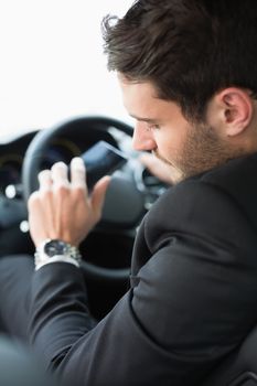 Young businessman checking his watch in his car