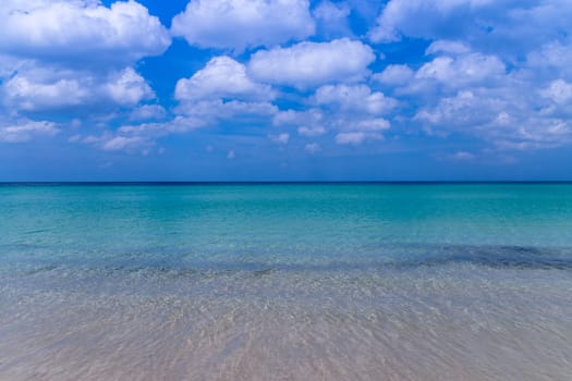 Sea beach with blue sky and yellow sand and some clouds above landscape
