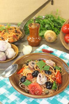 Spaghetti alla puttanesca with olives and capers on a napkin