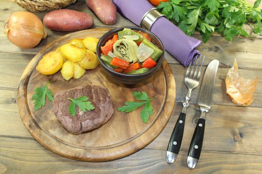 roasted ostrich steak with baked potatoes on a wooden board