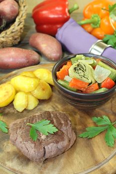 Ostrich steak with crispy baked potatoes on a wooden board