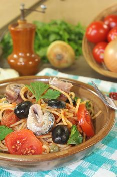 Spaghetti alla puttanesca with anchovy and tomatoes on a napkin