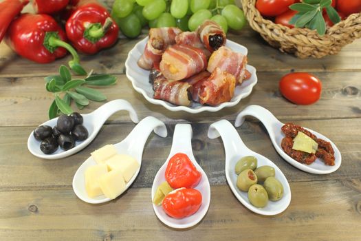 Tapas stuffed with prunes, figs and apricots and bacon on wooden plate