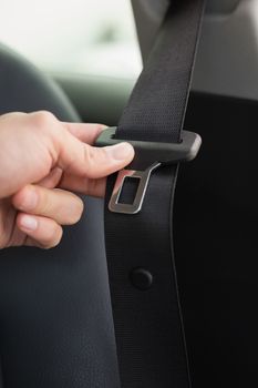 Man putting on his seat belt in his car