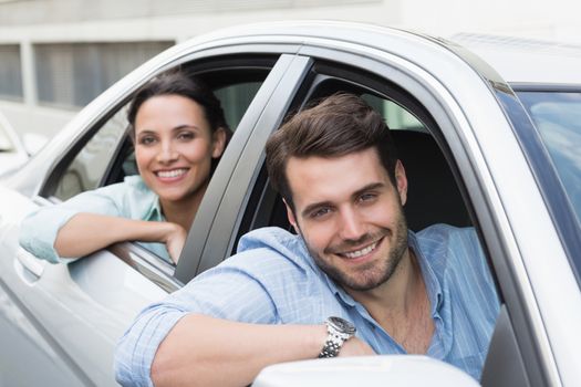 Young couple smiling at the camera in their car