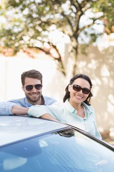 Young couple smiling at the camera outside their car