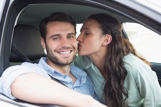 Young couple smiling at the camera in their car