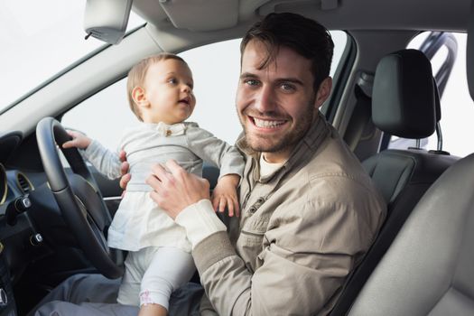 Father playing with baby in drivers seat in his car