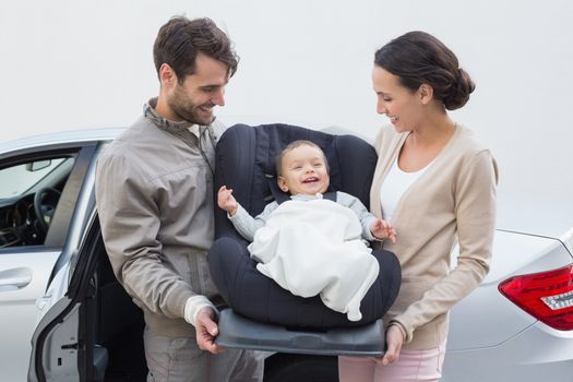 Parents carrying baby in his car seat out of the car