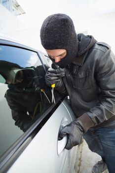 Thief breaking into a car in broad daylight