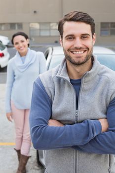 Young couple smiling at the camera outside their car