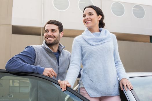 Young couple smiling together outside their car