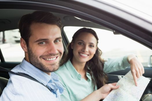Young couple looking at the map in their car