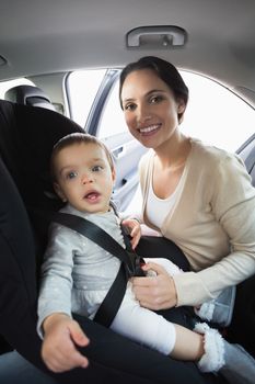 Mother securing her baby in the car seat in her car