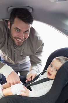 Father securing baby in the car seat in his car