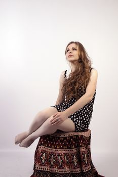 Young long-haired curly blonde woman sitting on chair, covered with mandala